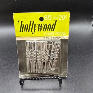 May include: A package of "Hollywood" brand hair pins. The package is yellow and silver with the text "85 pins" and "29¢". The hair pins are silver and are 2.5 inches long.