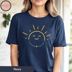 Könnte beinhalten: Marineblaues T-Shirt mit einem gelben lächelnden Sonnen-Motiv und dem Text "nurse mama" darunter.