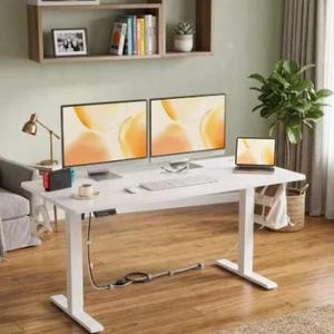 Peut inclure: Un bureau assis-debout blanc avec un plateau rectangulaire et deux pieds motorisés. La surface du bureau supporte deux écrans d'ordinateur, un ordinateur portable, un clavier, une souris et une petite tasse. Des câbles pendent sous le bureau.