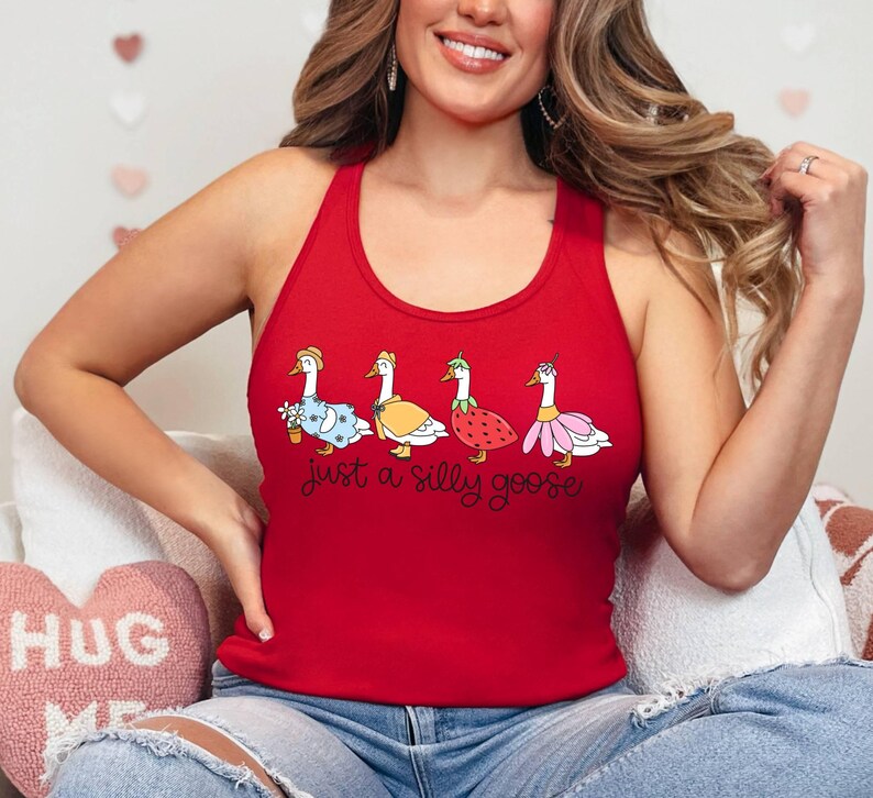 K&ouml;nnte beinhalten: Rotes Tanktop mit vier Cartoon-G&auml;nsen in verschiedenen Outfits. Unter den G&auml;nsen steht der Text "just a silly goose". Die G&auml;nse tragen ein Kleid, eine Jacke, ein Erdbeerkost&uuml;m und einen Rock.