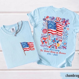 May include: Two light blue t-shirts. One has a small American flag on the pocket. The other has a large graphic of the American flag, fireworks, and text that reads "250th Anniversary The United States of America 1776-2026."