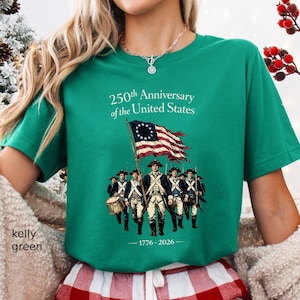 May include: Kelly green t-shirt with the text "250th Anniversary of the United States" and an illustration of soldiers and a flag. The flag has a circle of stars and red and white stripes. The shirt also has the dates 1776-2026.