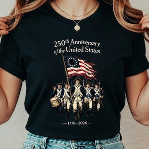 May include: Black t-shirt featuring a graphic commemorating the 250th Anniversary of the United States. The design includes an illustration of soldiers carrying a flag with red and white stripes and a circle of stars. The text "250th Anniversary of the United States" and "1776-2026" are also displayed.