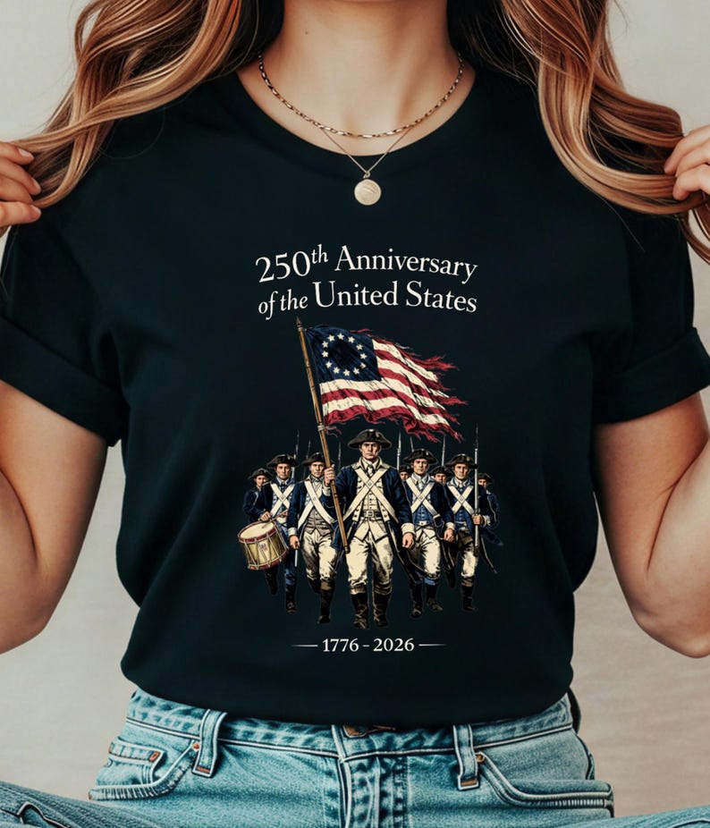 May include: Black t-shirt featuring a graphic commemorating the 250th Anniversary of the United States. The design includes an illustration of soldiers carrying a flag with red and white stripes and a circle of stars. The text "250th Anniversary of the United States" and "1776-2026" are also displayed.
