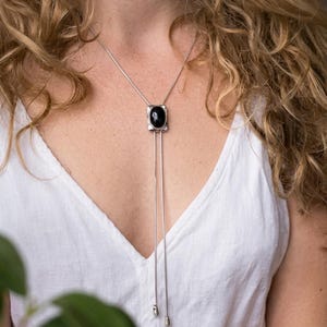 Woman wearing silver bolo tie necklace with black onyx over a blouse, showcasing elegant Y shape drape and minimalist western style suitable for both casual and dressy outfits.