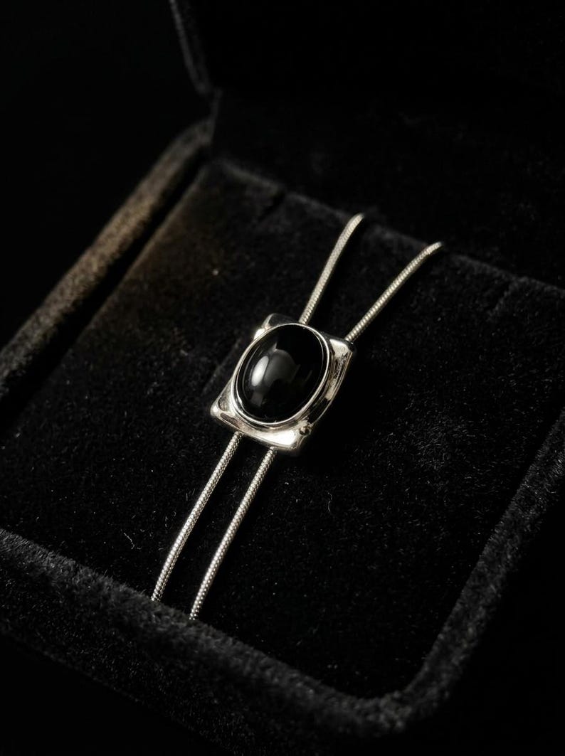 Silver bolo tie necklace with black onyx stone centerpiece displayed on a dark background, featuring a minimalist Y chain design, adjustable length, and sleek modern western style, perfect for women’s everyday jewelry or cowboy-inspired outfits.