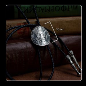 Classic U.S. half dollar bolo tie with black braided leather cord and vintage metal tips – handmade necklace for men who love retro Americana style.