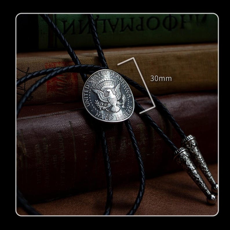 Classic U.S. half dollar bolo tie with black braided leather cord and vintage metal tips – handmade necklace for men who love retro Americana style.