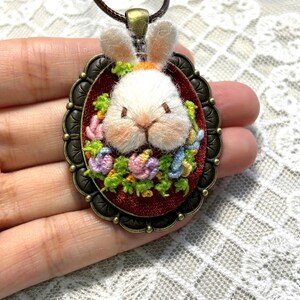 Close-up of cute 3D bunny pendant with colorful flowers, highlighting intricate hand embroidery craftsmanship