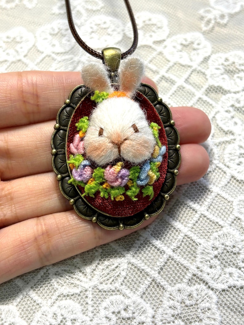 Close-up of cute 3D bunny pendant with colorful flowers, highlighting intricate hand embroidery craftsmanship