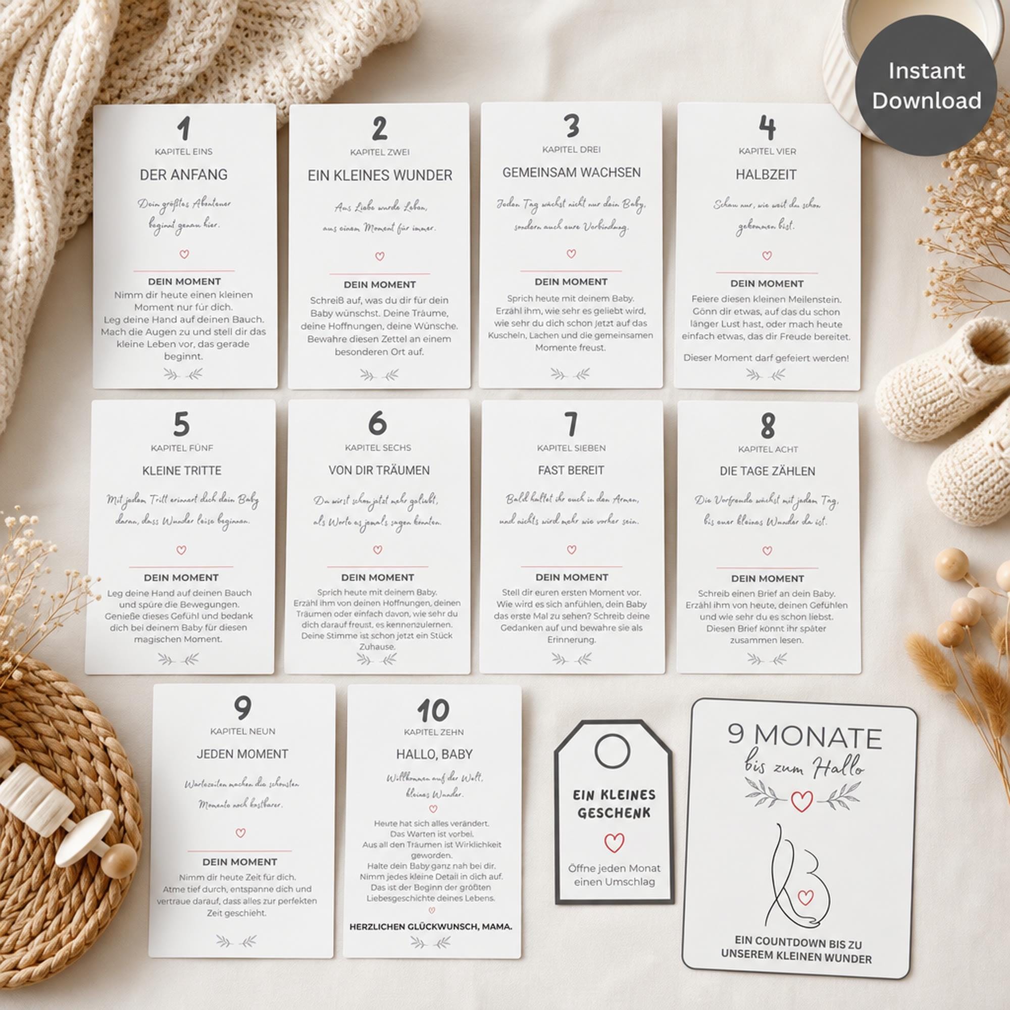 German pregnancy milestone cards numbered 1–10, plus “9 Monate” countdown card, arranged with baby accessories and knitwear