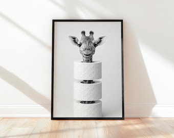May include: Black and white framed art print featuring a giraffe's head emerging from a stack of three toilet paper rolls. The giraffe has a smiling expression. The rolls have a repeating pattern.