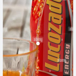 Pu&ograve; includere: Primo piano di una lattina di energy drink rossa con la scritta "Licozado" in giallo e la scritta "Energy" in bianco. Accanto, un bicchiere trasparente pieno di liquido arancione. La parola "Original" &egrave; visibile.