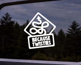 May include: White sticker with the text "BECAUSE TWISTIES" below a white diamond-shaped graphic with a squiggly line and an arrow. The sticker is on a window with a forest background.
