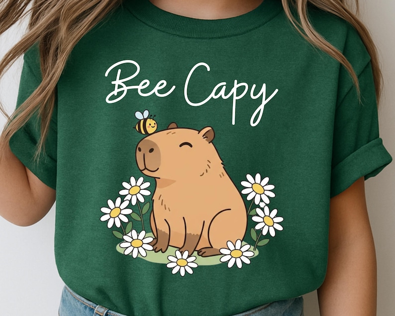 A green t-shirt with a cartoon image of a capybara surrounded by flowers and a bee.