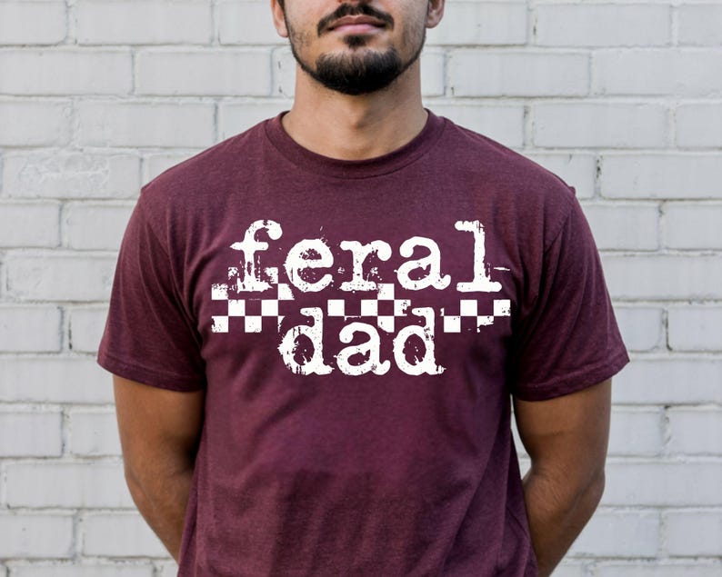 A man wearing a maroon t-shirt with the text "feral dad" printed on it.