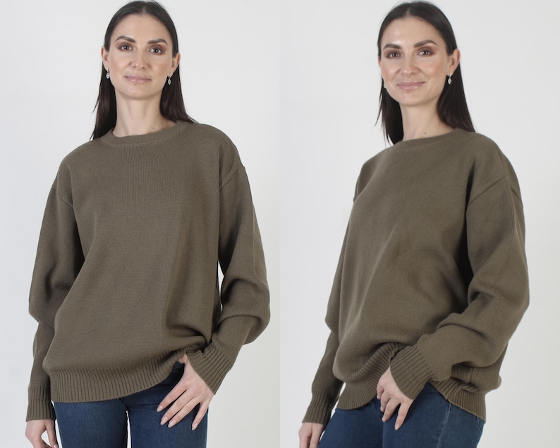 Puede incluir: Un su&eacute;ter verde oliva con cuello redondo y pu&ntilde;os y dobladillo acanalados. El su&eacute;ter est&aacute; hecho de un material de punto suave y se usa con jeans azules. El su&eacute;ter tiene mangas largas y un ajuste holgado.