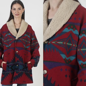 Könnte beinhalten: Ein roter Wollmantel mit cremefarbenem Shearling-Kragen und einem geometrischen Muster im Südwesten in Türkis, Marineblau und Lila. Der Mantel hat zwei Vordertaschen und zwei Knöpfe. Der Mantel ist mittellang.