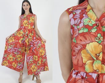 May include: A sleeveless jumpsuit in a vibrant floral print featuring yellow, orange, and purple flowers on a red background. The jumpsuit has a button-down front and wide legs, creating a retro, eye-catching look. The fabric appears to be lightweight, suitable for warmer weather.