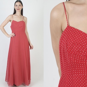 May include: A red maxi dress with white polka dots and a sweetheart neckline. The dress has thin straps and a flowing skirt.