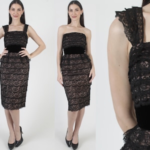 May include: A black lace dress with a velvet belt. The dress has a square neckline and a fitted silhouette. The lace detailing adds texture and visual interest to the garment. The dress is knee-length.