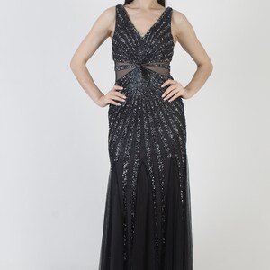 May include: A black formal gown with a V-neckline and a fitted bodice. The bodice and upper skirt are embellished with sparkling sequins in a radiating pattern. The lower skirt is a flowing, sheer fabric. The dress is sleeveless.