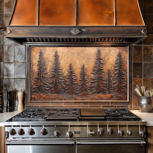 Könnte beinhalten: Ein Edelstahlherd mit einer Kupferhaube und einer Kupferrückwand mit einem erhabenen Design eines Waldes. Die Rückwand hat ein rustikales, waldiges Aussehen.