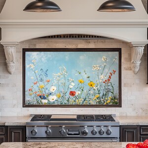 Pode incluir: Uma pintura emoldurada de um campo de flores silvestres em tons de azul, amarelo, vermelho e branco contra um céu azul claro. A pintura está montada acima de um fogão de aço inoxidável com quatro queimadores e uma grelha preta.