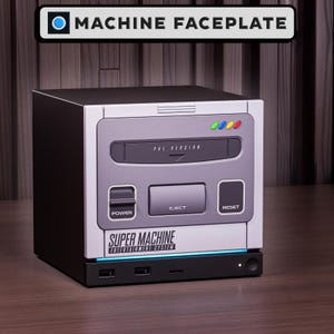 Könnte beinhalten: Eine schwarze und hellgraue Videospielkonsole mit einer Frontplatte, die mit "SUPER MACHINE ENTERTAINMENT SYSTEM" und "PAL VERSION" beschriftet ist. Die Konsole verfügt über einen Netzschalter, eine Auswurftaste, eine Reset-Taste, vier kleine farbige Kontrollleuchten und zwei USB-Anschlüsse.