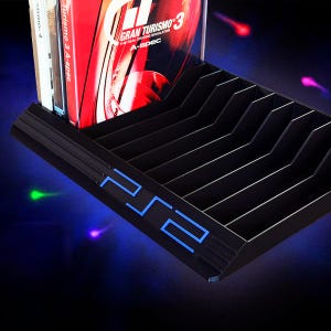 Puede incluir: Organizador de juegos de PS2 negro con logotipo de PS2 azul iluminado. El organizador contiene varias carcasas de juegos, incluido Gran Turismo 3. El diseño presenta divisores en ángulo para facilitar el acceso a los juegos. Una solución de almacenamiento elegante.