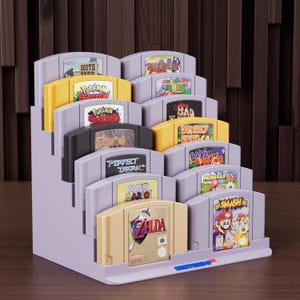 May include: A purple tiered display stand holding several Nintendo 64 game cartridges. The cartridges are in various colours, including yellow, black, and beige, with game titles such as "Zelda", "Mario", and "Donkey Kong". The stand has the Nintendo 64 logo.