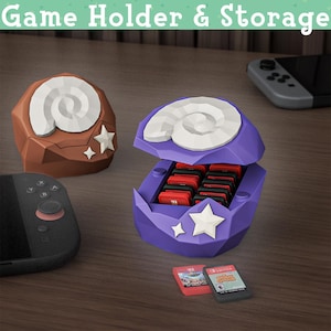 May include: Purple and brown game cartridge holders shaped like shells, with white spiral designs and star accents. The purple holder is open, revealing several game cartridges. The text "Game Holder & Storage" is at the top.