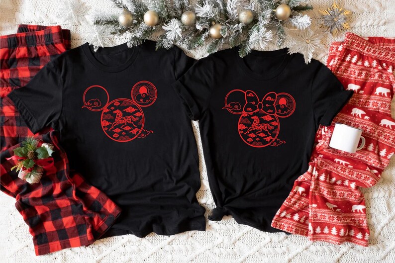 May include: Black t-shirts with red graphic designs featuring a horse and clouds in a Mickey Mouse head shape. Red and black plaid pajama pants and red pajama pants with white bear and tree patterns are also visible.