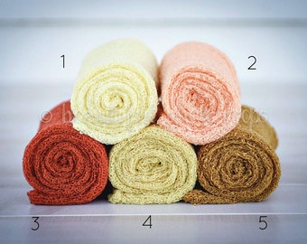 May include: Five rolls of fabric in different colors, including rust, cream, peach, and brown. The fabric is a delicate, open weave with a lacy texture. The rolls are numbered 1 through 5.