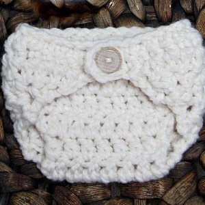 May include: White crocheted baby diaper cover with a white button.