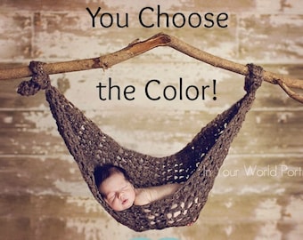 May include: A baby sleeping in a brown crocheted hammock hanging from a branch. The text "You Choose the Color!" is above the hammock.