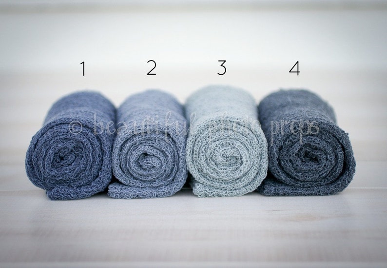 May include: Four rolled up fabric swaddles in shades of blue, labeled 1 through 4.
