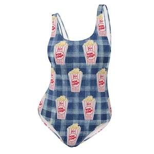 May include: A blue and white gingham swimsuit with a repeated pattern of red and white popcorn boxes. The text on the boxes reads "Fresh Pop Corn".