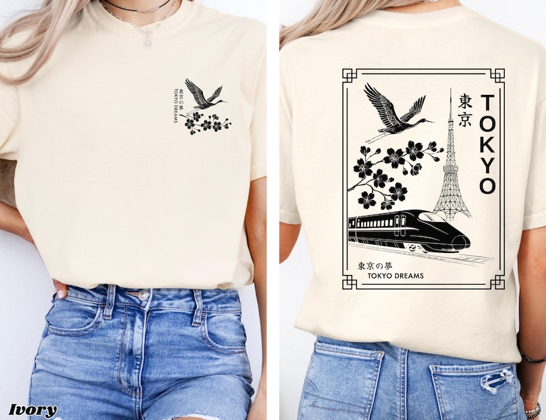 May include: A cream colored t-shirt with a black graphic design featuring a crane, cherry blossoms, a train, and the Tokyo Tower. The text on the shirt reads "Tokyo Dreams" and "東京の夢".