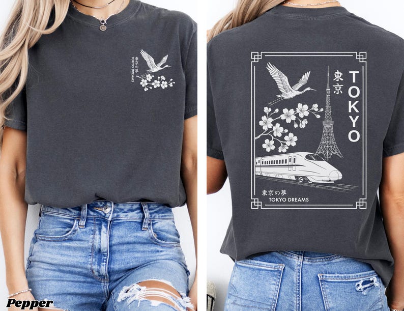 May include: A dark gray t-shirt with a white graphic print of a crane, cherry blossoms, a train, and the Tokyo Tower. The text "TOKYO DREAMS" is printed below the graphic.