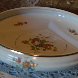 May include: A white, divided serving dish with a gold rim and floral accents. The dish features a central floral design with red, orange, and blue flowers. Additional floral patterns are scattered around the rim, creating a vintage aesthetic.
