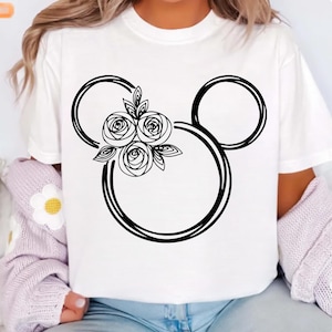 May include: White t-shirt featuring a black floral Mickey Mouse design. The design includes three roses and leaves within the iconic mouse silhouette. The shirt is a casual, everyday wear item.