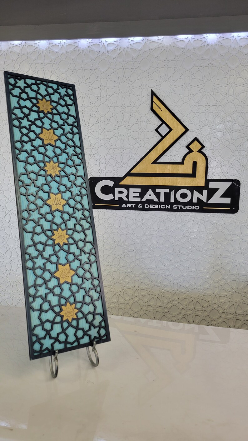 May include: A rectangular, turquoise and black decorative panel with a geometric star pattern and gold accents. The panel is supported by a metal stand. The CreationZ Art & Design Studio logo is visible in the background.