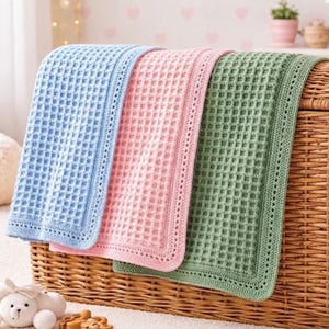May include: Three rectangular crochet blankets in light blue, soft pink, and sage green. Each blanket features a consistent waffle-like grid texture throughout the centre and a decorative, perforated border along all four edges of the fabric.