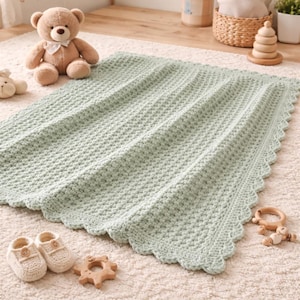 May include: A soft, mint green baby blanket with a textured, woven pattern and a scalloped edge. The blanket is surrounded by baby items, including a teddy bear, baby shoes, and wooden toys. The blanket measures approximately 40 x 50 inches.