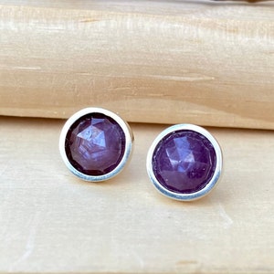 May include: A pair of silver stud earrings with purple faceted gemstones.