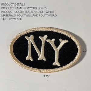 May include: An oval-shaped embroidered patch featuring the letters NY in an off-white bone-like font on a black background with an off-white border. The patch measures 3.25 inches wide by 2.0 inches high as indicated by the text in the image.