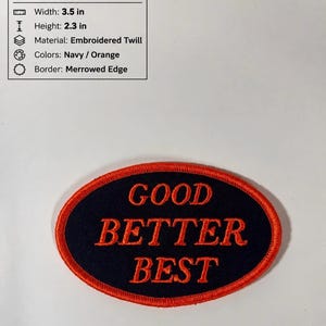 May include: An oval embroidered twill patch with a navy blue background and an orange merrowed edge. The text GOOD BETTER BEST is stitched in orange across the center. The patch measures 3.5 inches in width and 2.3 inches in height.