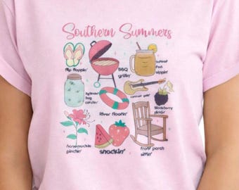 May include: A light pink t-shirt with the words "Southern Summers" and illustrations of summer activities. The design includes a grill, flip-flops, a mason jar, a guitar, and a rocking chair.