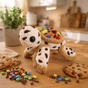 Peut inclure: Une peluche tortue crochetée avec une tête et des membres couleur crème ornés de taches brunes. La carapace de la tortue est en laine marron clair texturée et décorée d'accents ronds et colorés rappelant des bonbons rouges, bleus, orange et jaunes.